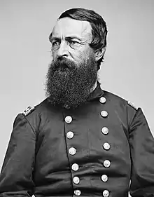 Black and white photo shows a heavily bearded man in a dark military uniform that has two rows of buttons.