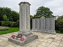 Two memorials, one a four-sided stone pillar, the other a stone arc. Both are inscribed with names
