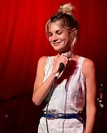Songwriter Amy Allen standing against a red background.