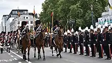 Soldiers in elaborate uniforms parade on horseback
