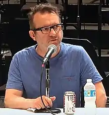 Mark Anthony-Turnage speaks into a microphone during a conference.