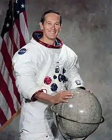 man in space suit, hands on globe, American flag in background